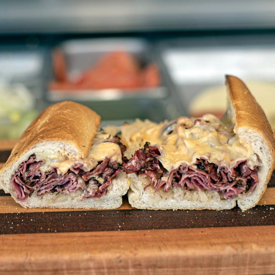 Pastrami Reuben cut in half showing thick New York style black pastrami, sauerkraut, and melted swiss cheese