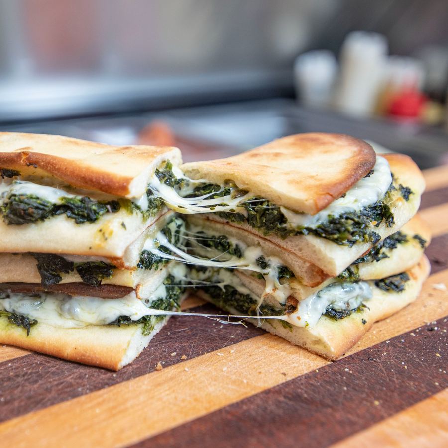 Riccotti's famous spinach pie pulled apart showing layers of seasoned spinach, pepperoni, and gooey melted provolone