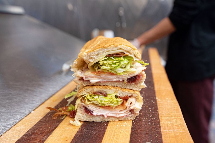 Turkey Special sub in cross-section showing oven roasted turkey, bacon, melted provolone, and cranberry sauce stacked high
